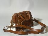 a brown purse with a strap and a tag on it
