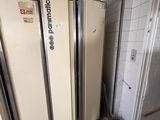 Plusieurs réfrigérateurs sont alignés contre un mur dans une pièce.
