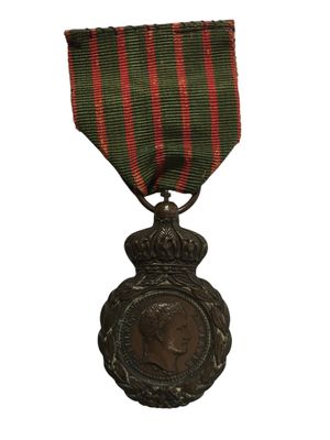une vieille médaille ornée d'un ruban rouge et vert sur fond blanc