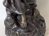 bronze statue of a woman holding a baby on a rock