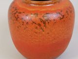 an orange vase sitting on a table with a white background