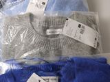 three pairs of men ' s sweaters in plastic bags on a counter