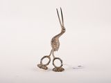 une sculpture en argent représentant un oiseau avec des ciseaux à l'intérieur