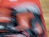 photo floue d'une personne au guidon d'une moto rouge sur un plancher en bois