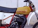a red and yellow dirt bike parked in front of a white wall