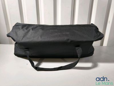 une photo montrant un sac noir posé sur une table blanche