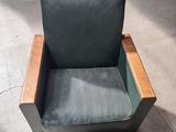 un fauteuil en cuir vert avec une structure en bois, posé à même le sol