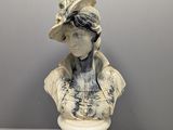 statue d'une femme coiffée d'un chapeau, posée sur un socle blanc