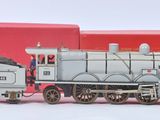 un petit train en jouet posé à côté d'une boîte rouge