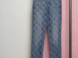 a pair of jeans hanging on a clothes rack in front of a pink wall