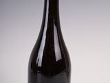 a black bottle with a gold cap sitting on a white surface