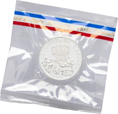 a close up of a coin in a plastic bag on a white background