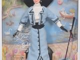 Poupée Barbie de collection représentant une femme en robe bleue, coiffée d'un chapeau et tenant une canne