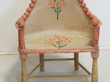 a small wooden chair with a flower design on it