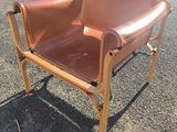 un fauteuil en cuir marron posé sur le gravier
