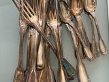 a lot of silver spoons and forks on a glass table