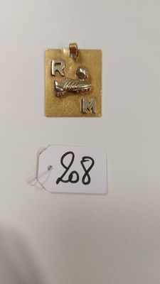 gros plan d'un pendentif plaqué or sur une surface blanche
