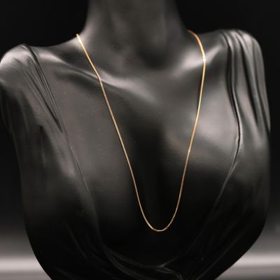 a black mannequin bust with a gold chain on it
