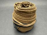 un rouleau de corde de jute posé sur une surface grise