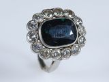 gros plan d'une bague avec une pierre bleue entourée de diamants