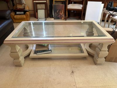 une table basse avec un plateau en verre, sur laquelle est posé un livre