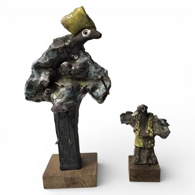 deux sculptures représentant un homme et une femme, posées sur un socle en bois