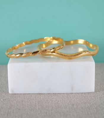 two gold rings sitting on top of a marble block