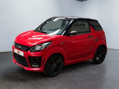 La voiture rouge est garée dans une grande pièce au sol noir.