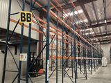 Le grand entrepôt est rempli de rayonnages et de palettes destinés au stockage.