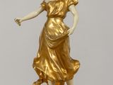 statue d'une femme vêtue d'une robe dorée et tenant une fleur