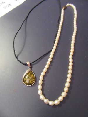 collier de perles avec un pendentif en pierre jaune monté sur un cordon noir
