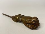 a small bronze hand holding a broom on a white surface