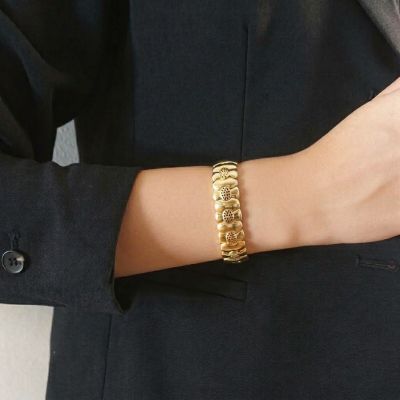 une femme vêtue d'un tailleur noir et portant un bracelet en or