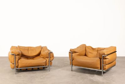 two brown leather chairs sitting next to each other on a cement floor