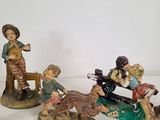 several figurines of people sitting on a bench with a dog on a leash