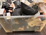 un grand bac en plastique rempli de sacs, posé par terre