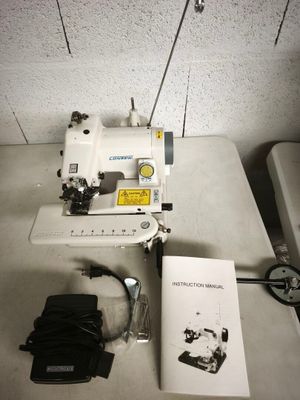 une machine à coudre blanche posée sur une table, à côté d'un livre