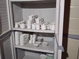 a small cabinet with a lot of dishes and cups on it