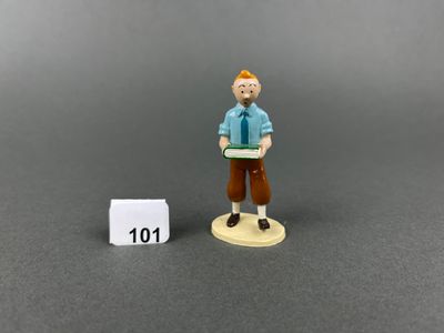 miniature figurine of a man holding a book next to a white block
