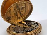 a gold pocket watch sitting on a white surface