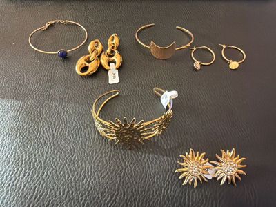 plusieurs paires de boucles d'oreilles et de bracelets en or posés sur une table