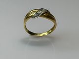 gros plan d'une bague en or avec des diamants sur une surface blanche