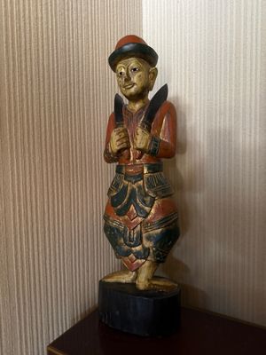 une statue en bois représentant un homme debout sur une table