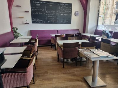 de nombreuses tables et chaises dans un restaurant, avec un tableau noir accroché au mur