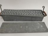 an old metal box with holes and a piece of metal