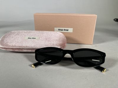 black sunglasses with gold accents and a pink case on a table