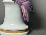 a figurine of a pink parrot sitting on top of a white vase