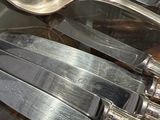 a lot of silver spoons and knives on the table