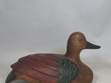wooden carved duck with green and red feathers sitting on a white surface