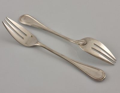 une paire de fourchettes et de cuillères en argent posées sur une surface blanche